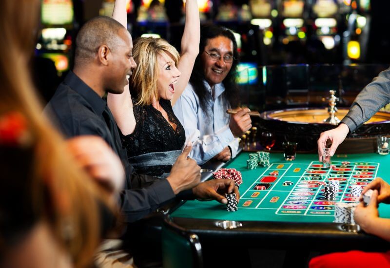 A young woman is having fun at a casino table with friends in Black Hawk, CO, & the Denver metro