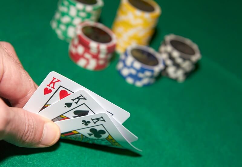 Player holding a strong 3-card poker hand at a casino table in Black Hawk, CO, & the Denver metro